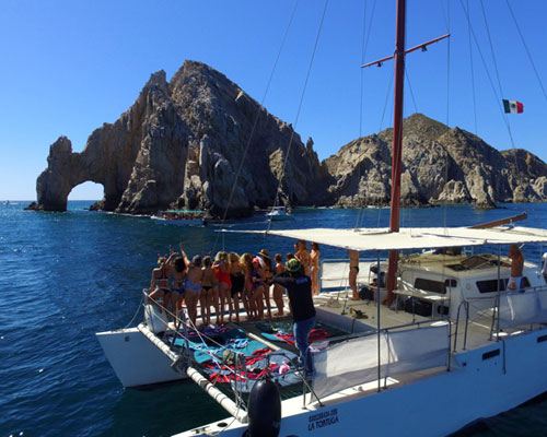 Guests on the bow of a catamaran in front of El Arco in Cabo San Lucas