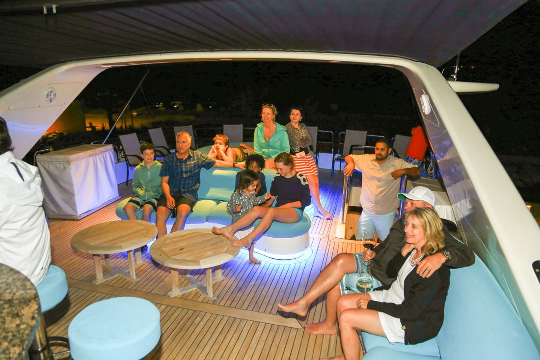 Guests gathered for an evening event aboard a lit-up yacht