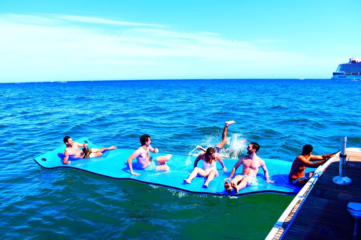 Guests relaxing on a floating mat during a swim stop from a charter yacht