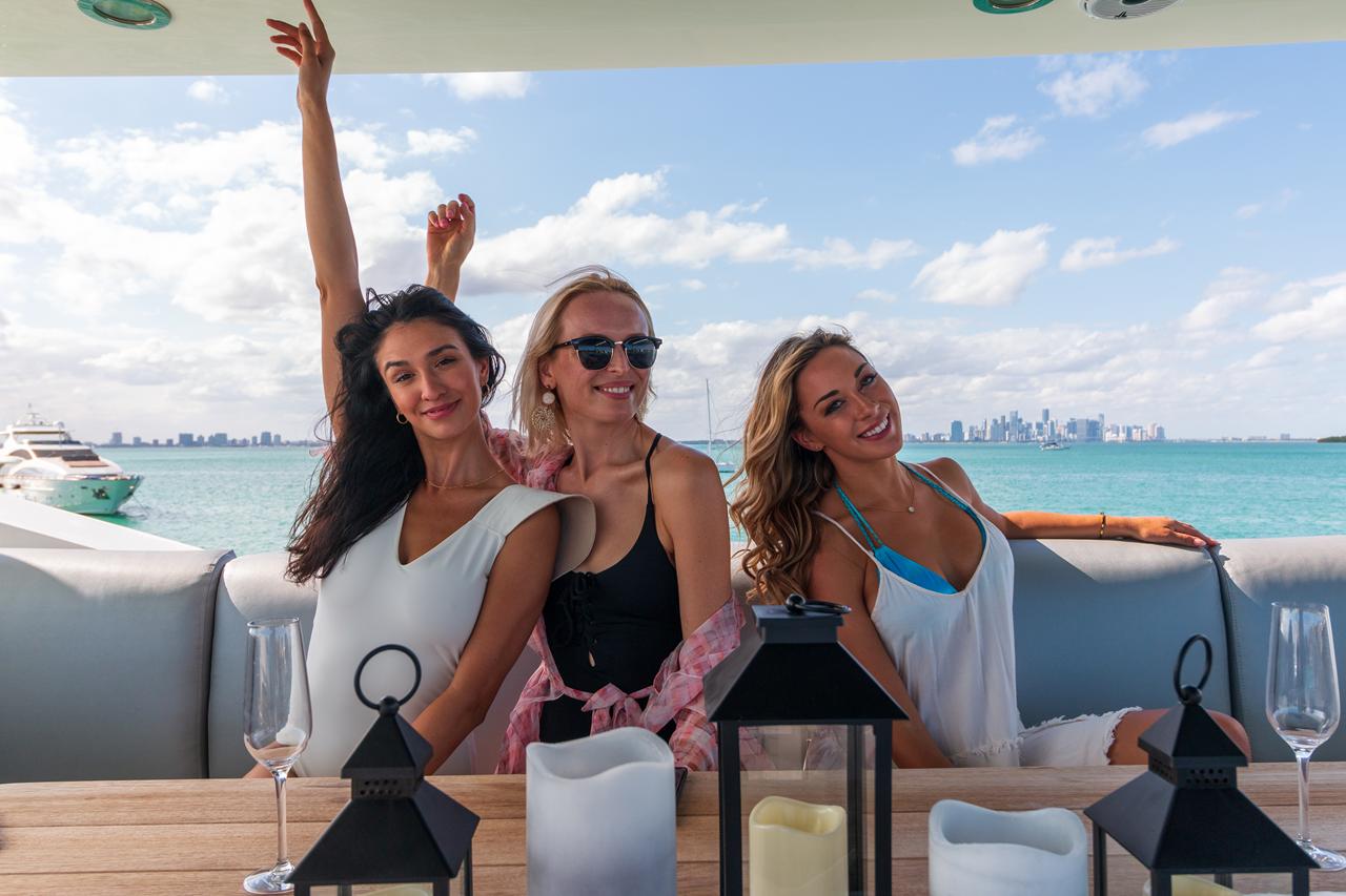 Friends toasting at a yacht's aft-deck table with the Miami skyline in the distance