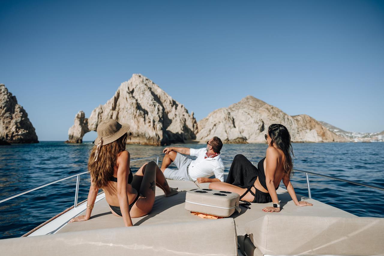 Guests relaxing on the bow of a yacht facing the Land's End rocks in Cabo San Lucas