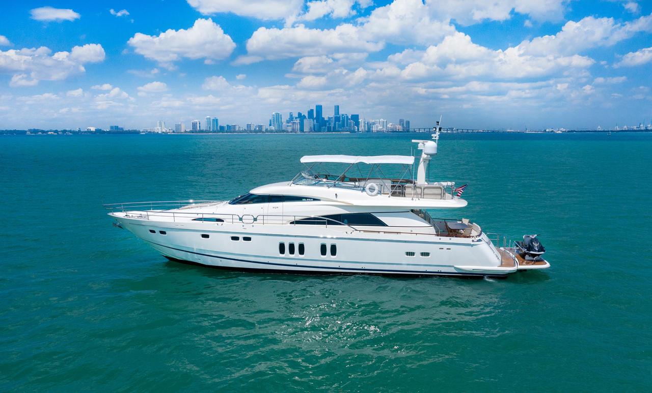A motor yacht on turquoise Biscayne Bay water with the downtown Miami skyline on the horizon