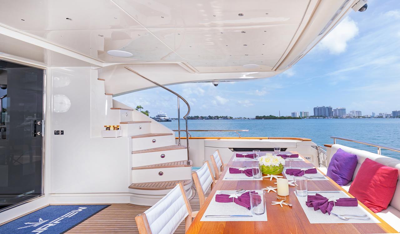 An outdoor dining table set on the deck of a motor yacht