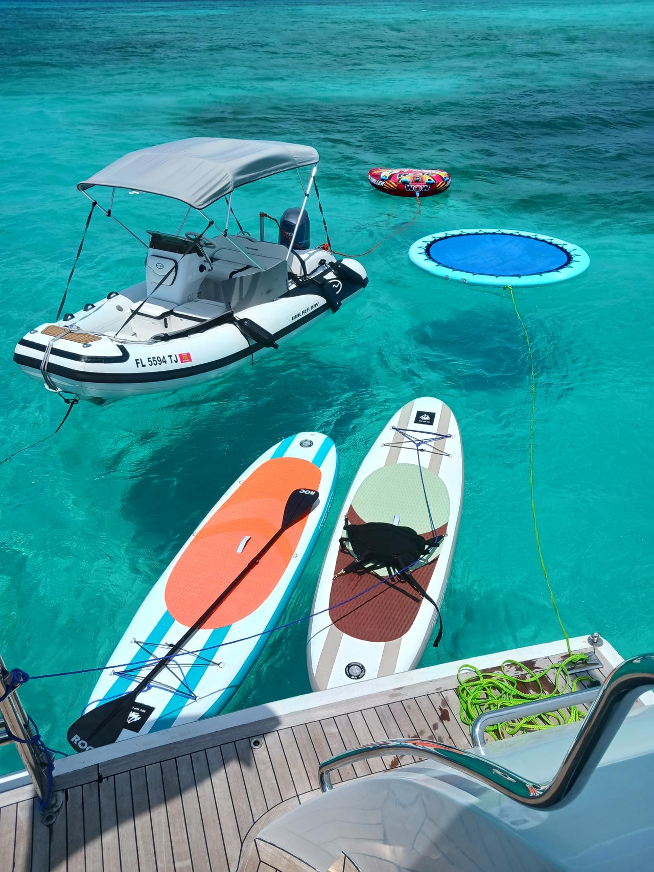 Paddleboards and a floating swim pool beside an anchored yacht