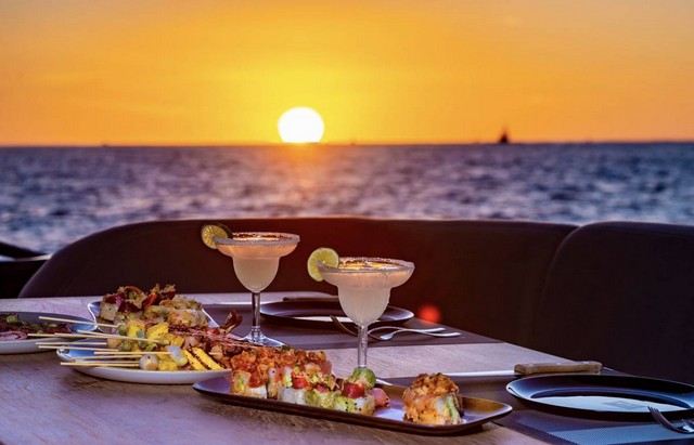 Margaritas and appetizers on a yacht's deck as the sun sets over the sea