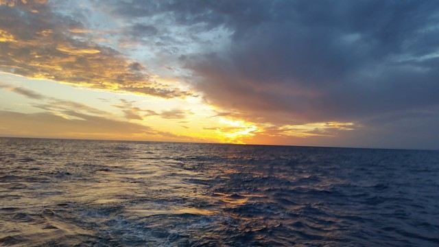 The sun dropping toward the horizon over open water